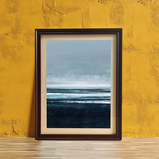 Abstract seascape print framed in Coffee (dark brown) wood with a mount/mat, leaning on a light wooden surface against a vibrant yellow textured wall. The print features layered shades of deep blue, light blue, and white.