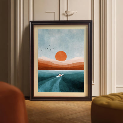 Abstract art print framed in Coffee (dark brown) wood with a mount/mat, leaning on a wooden floor against a paneled cabinet door/wall. Shows the print in a home setting with a glimpse of orange and mustard yellow furniture in the foreground.