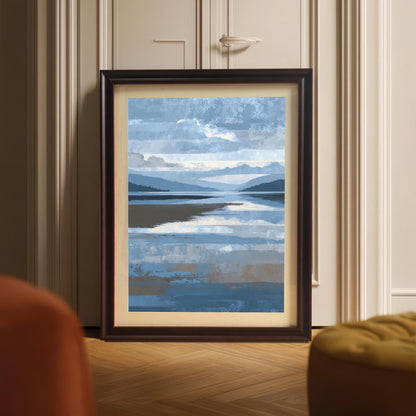 Abstract blue and brown landscape art print framed in dark Coffee wood with a light mount, leaning against a white panel door on a wooden floor, partially visible behind an orange chair and yellow ottoman.