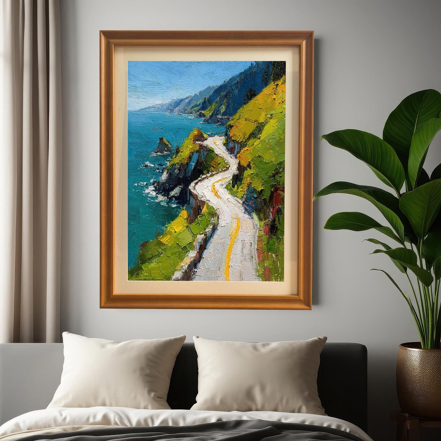 A framed print of a vibrant oil painting of a winding coastal road hanging on a gray wall above a bed with white pillows and a gray comforter. The frame is Orange (light brown wood color).