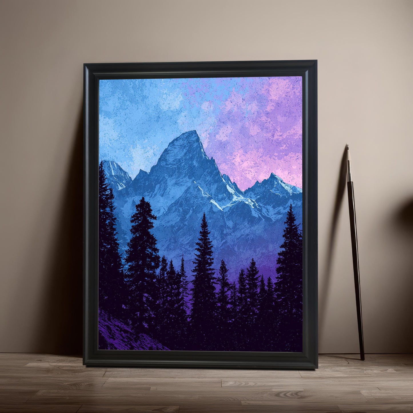 The mountain art print is framed with a Black Frame (no mount) and propped on a wooden floor against a neutral taupe wall. A pencil or thin decorative object leans against the wall to the side.