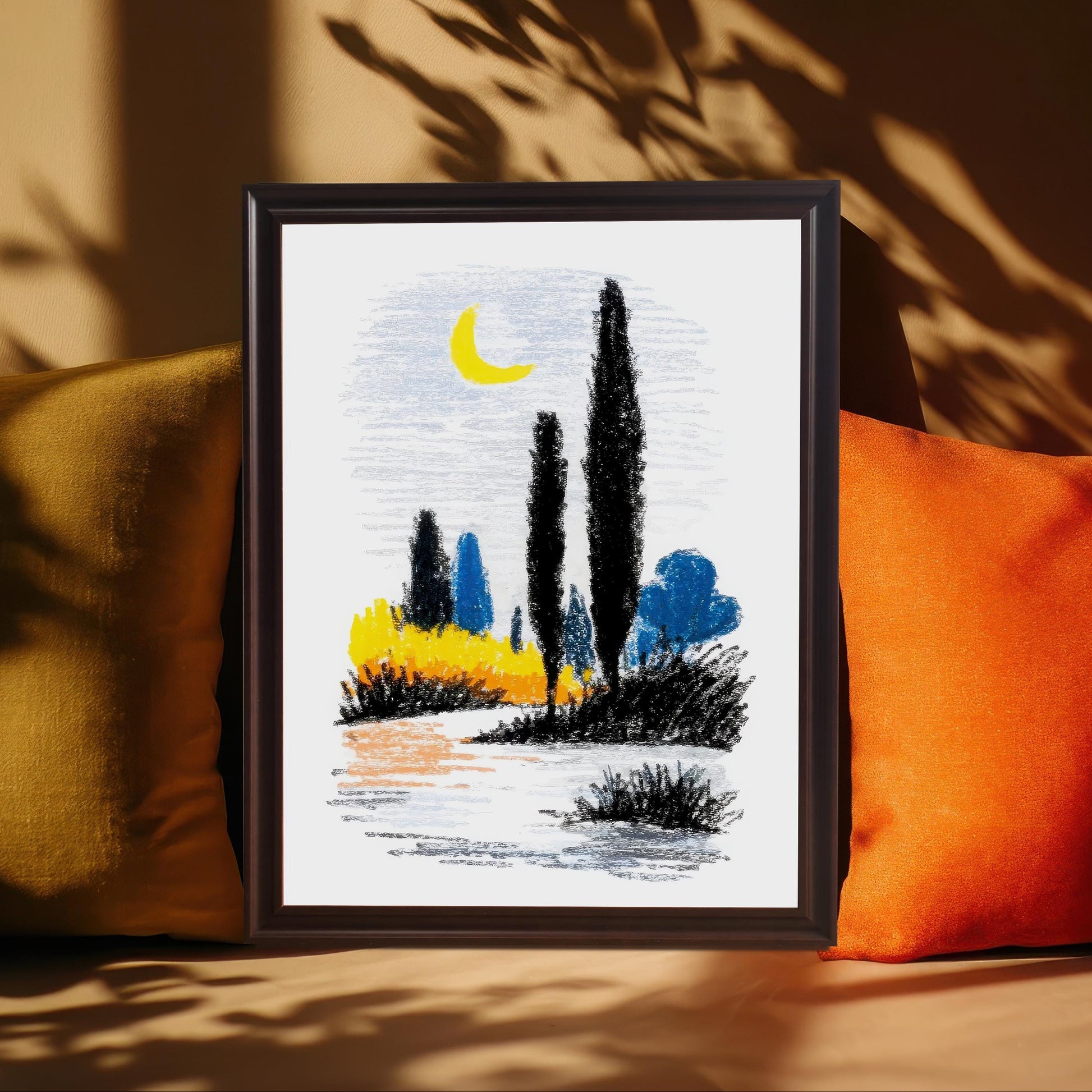 A close-up of the abstract landscape print in a dark brown/coffee frame, leaning against a tan surface between a mustard yellow and a bright orange throw pillow, with sunlit plant shadows cast across the background.