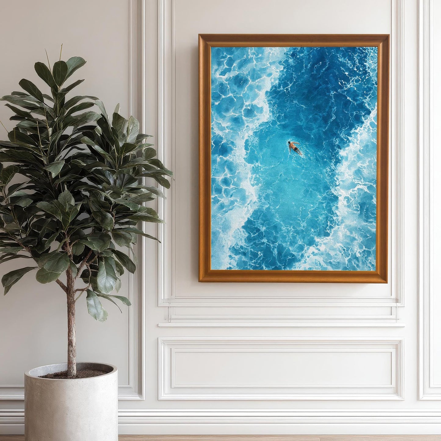 The framed ocean art print in an Orange/light brown frame with no mat, hanging on a white wainscoted wall next to a tall potted plant.