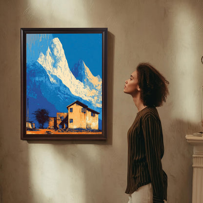 Framed art print with stylized white and blue mountains and an orange house, hanging on a textured wall, with a woman looking at the artwork.