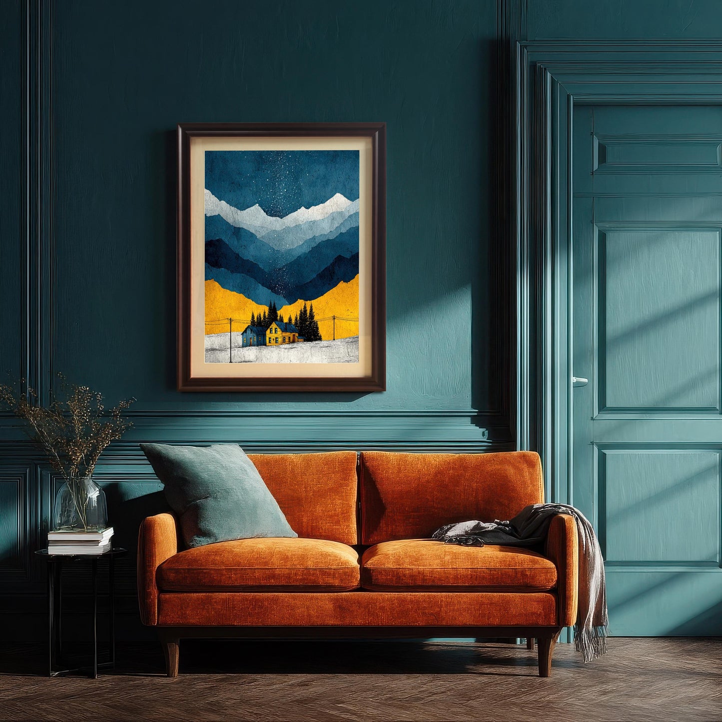 The framed art print, featuring a snowy mountain and yellow house under a starry sky, hanging above an orange velvet sofa in a room with dark teal/green paneling and a matching door. The frame is a dark, Coffee color with a mat.