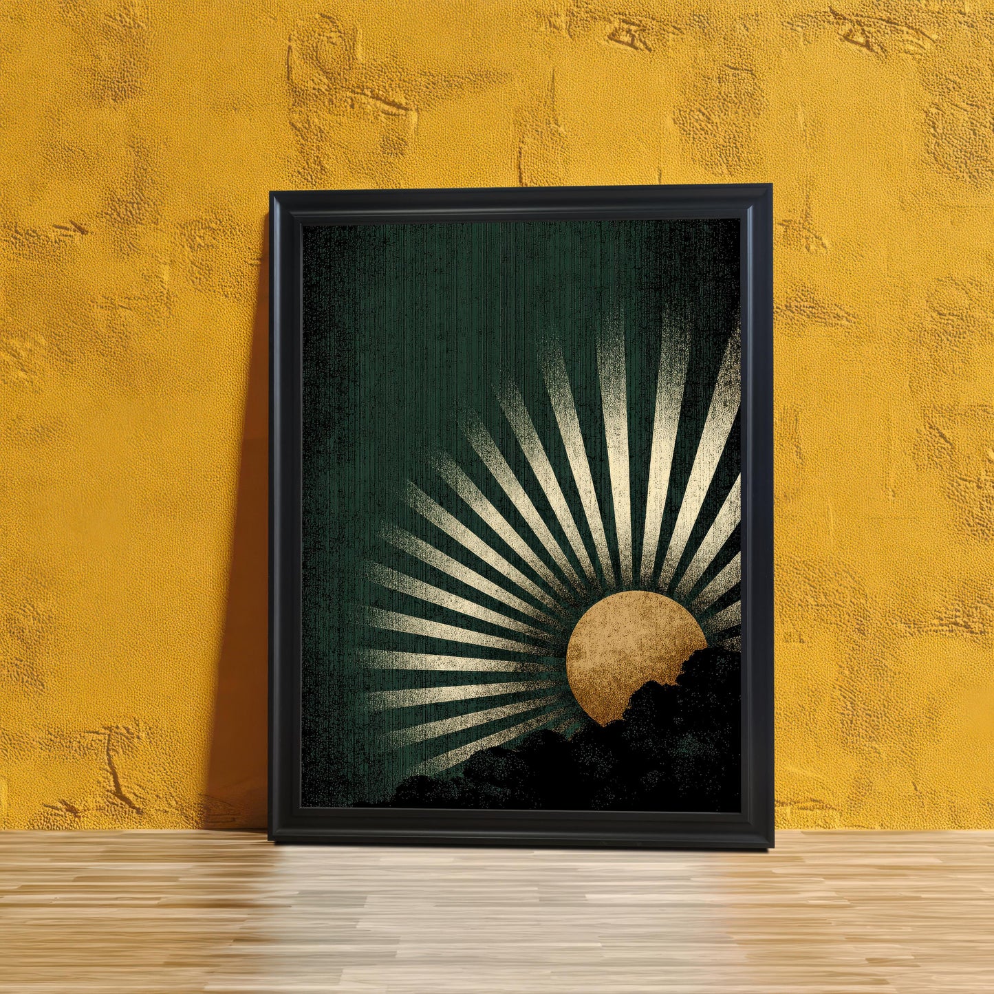 The dark green and gold sunburst art print in a Black Frame without a mount, leaning against a textured, vibrant yellow wall, with a light wood floor.