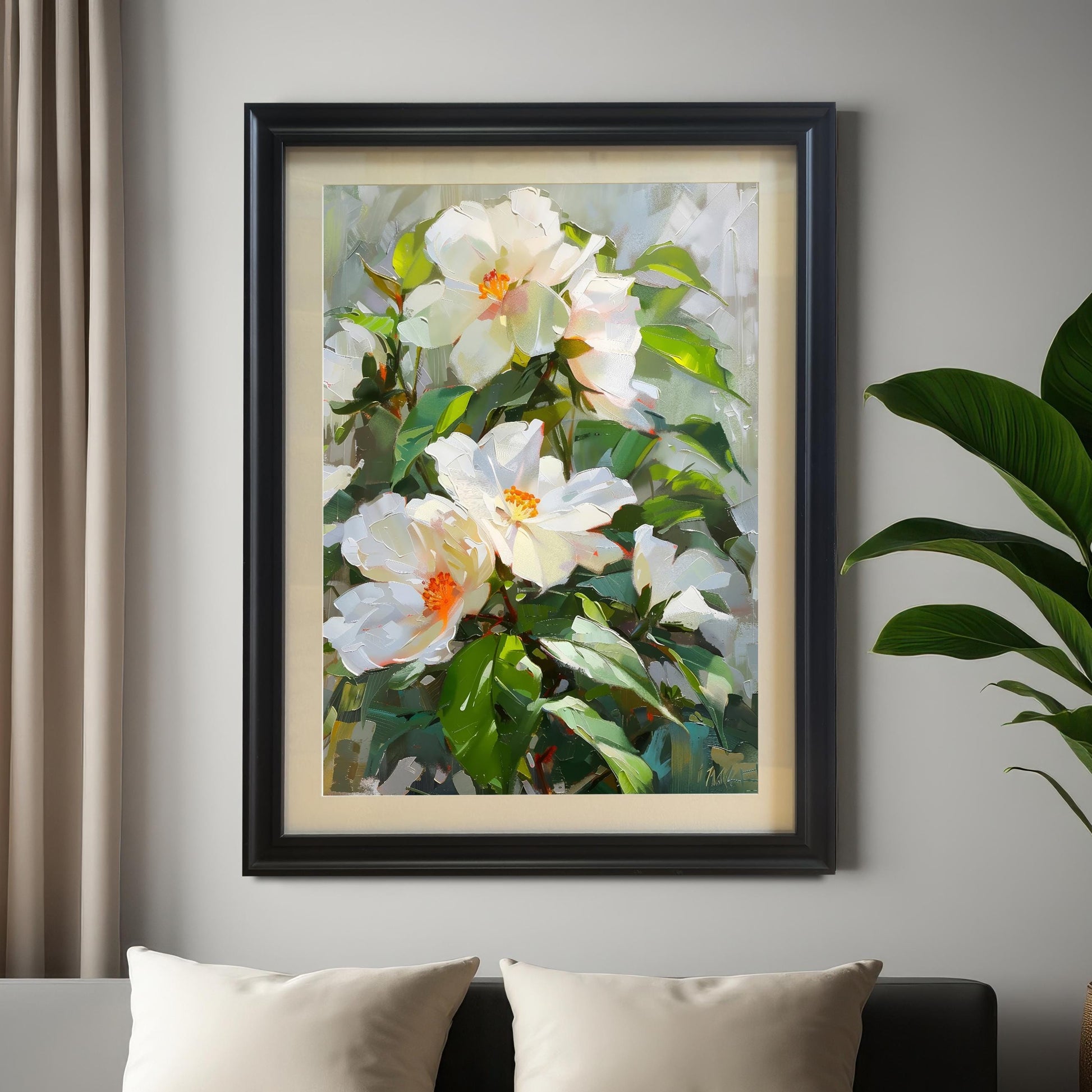 A textured oil painting of white roses or hibiscus-like flowers with orange centers and green leaves, displayed in a black frame on a light gray wall above a bed with cream pillows and next to a large potted plant.