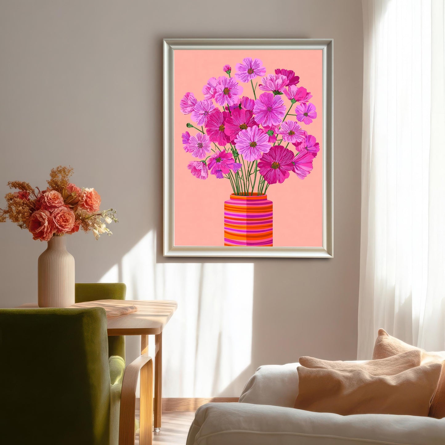 Brightly lit dining and living area showing the framed art print of pink Cosmos flowers in a striped vase, hanging on a light beige wall above a sofa. The frame is silver/white.