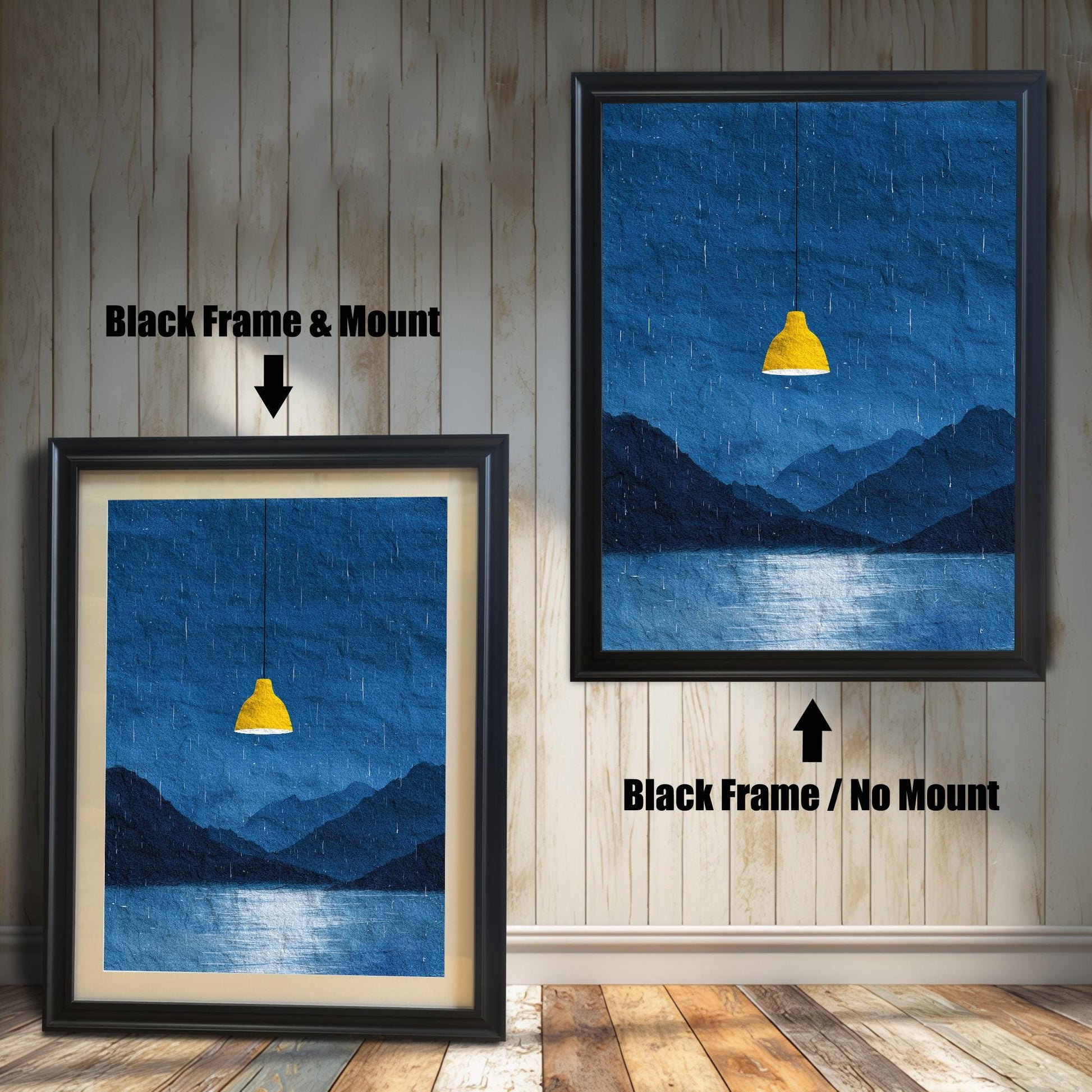 A comparison image showing two framed art prints on a wooden wall. The print on the left is in a Black Frame & Mount (black frame with a light mat). The print on the right is in a Black Frame / No Mount (black frame, no mat). Both feature the dark blue rainy landscape with the yellow lamp.