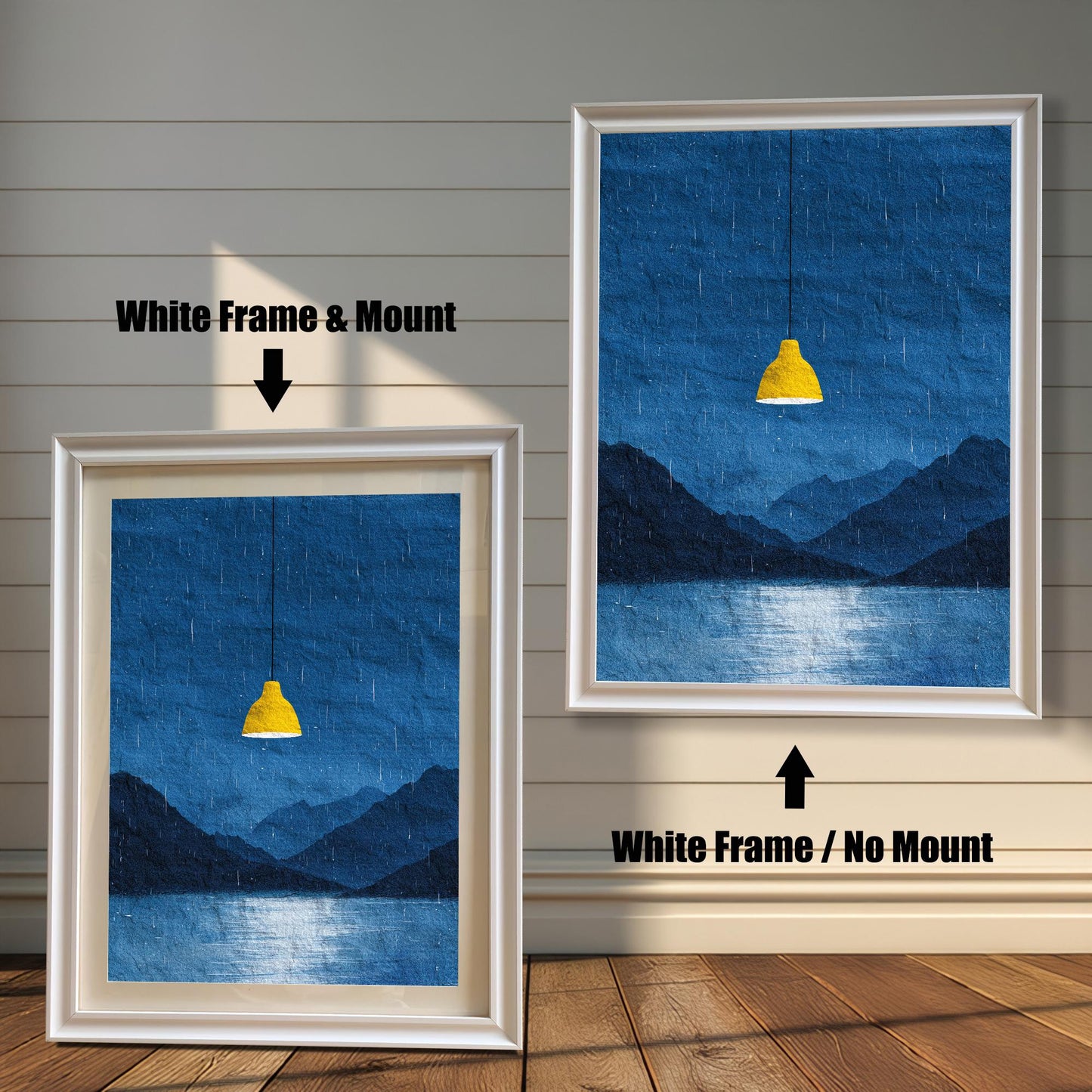 A comparison image showing two framed art prints on a wooden wall. The print on the left is in a White Frame & Mount (white frame with a light mat). The print on the right is in a White Frame / No Mount (white frame, no mat). Both feature the dark blue rainy landscape with the yellow lamp.