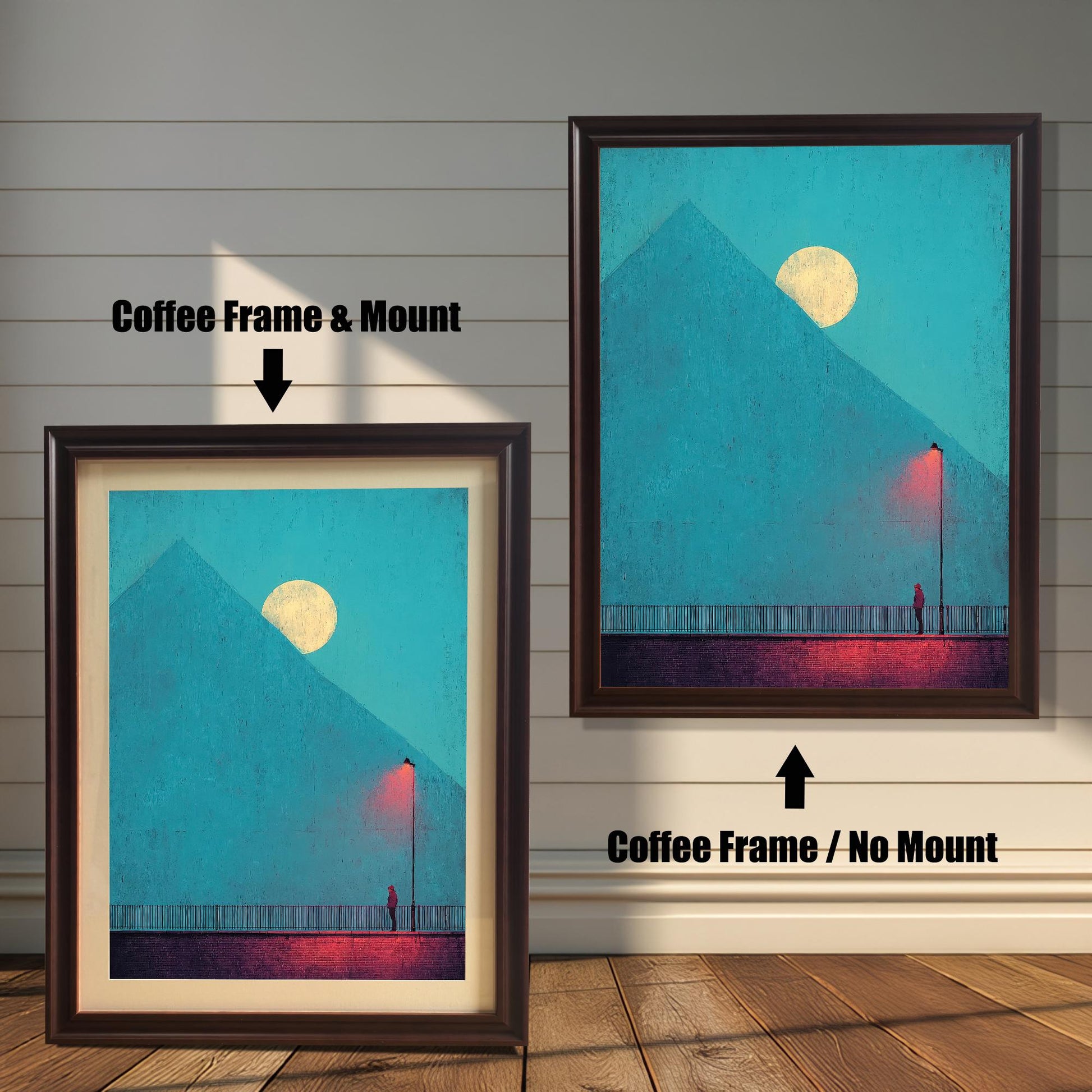 Comparison image showing two framed art prints against a white wainscoting wall. The left print uses a Coffee Frame & Mount (matting). The right print uses a Coffee Frame / No Mount. The art depicts a minimal landscape with a figure, a red lamp post, and a pyramid under a moon.