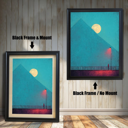 Comparison image showing two framed art prints against a white wainscoting wall. The left print uses a Black Frame & Mount (matting). The right print uses a Black Frame / No Mount. The art depicts a minimal landscape with a figure, a red lamp post, and a pyramid under a moon.