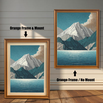 A comparison image showing two framed art prints on a wooden wall. The print on the left is in an Orange Frame & Mount (golden/orange frame with a light mat). The print on the right is in an Orange Frame / No Mount (golden/orange frame, no mat). Both feature the mountain and lake design.