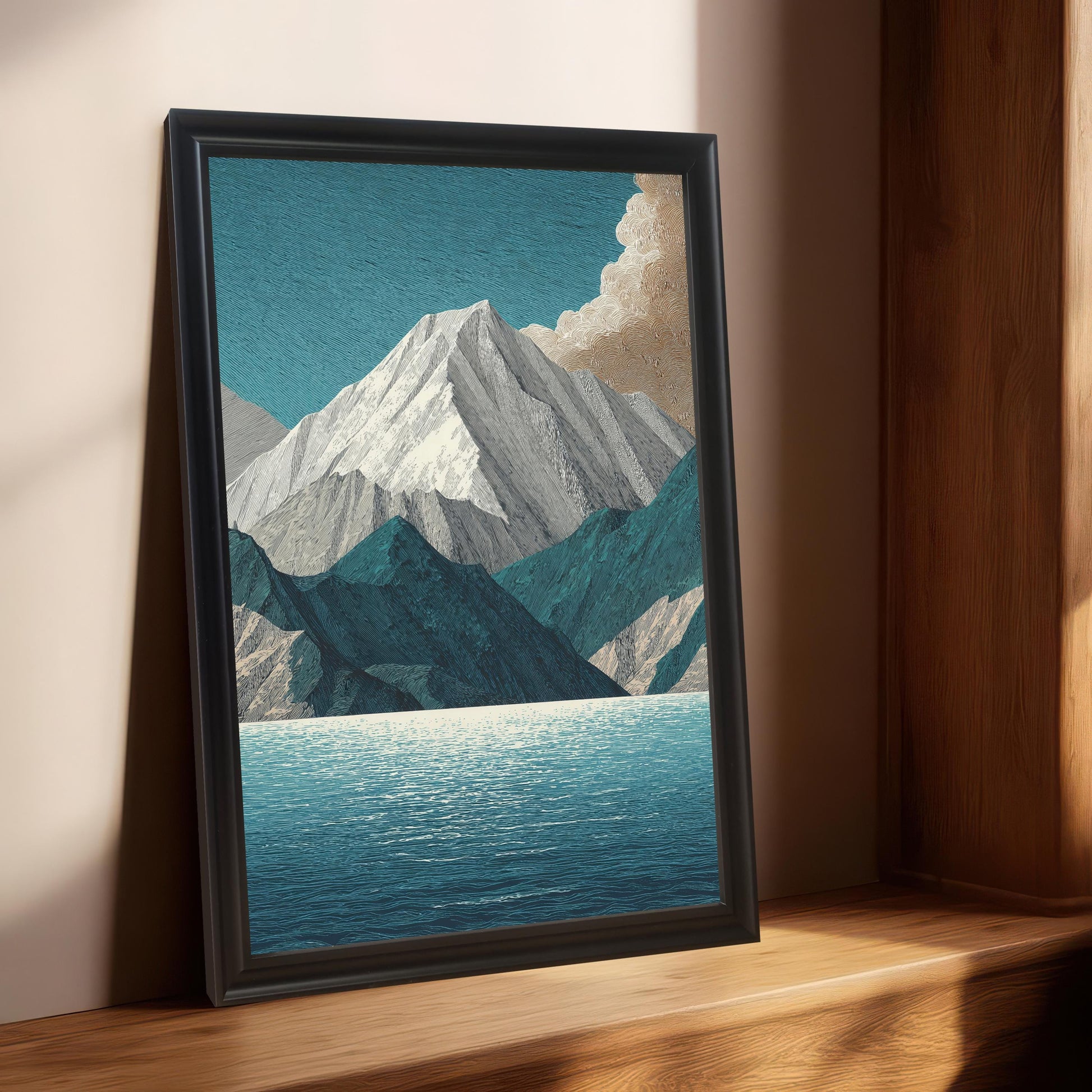 The mountain and lake art print in a black frame, leaning on a wooden window sill or shelf against a light beige wall. Sunlight streams in from the side, illuminating the frame and the wooden surface.