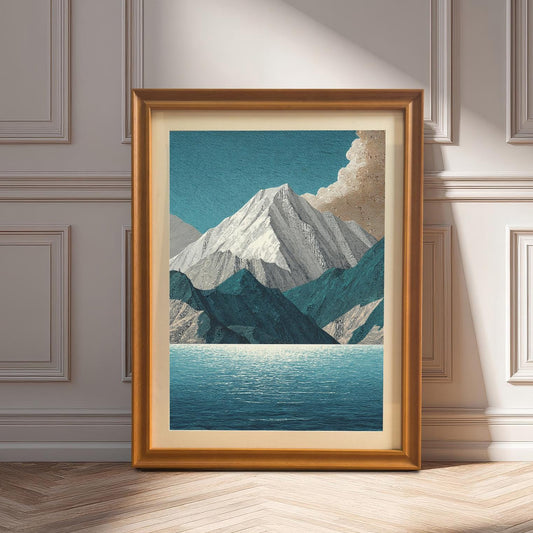 A framed art print of the mountain and lake design in an Orange (golden/bronze) frame with a mount, leaning against a white wainscoting wall on a herringbone floor. Sunlight creates deep shadows.