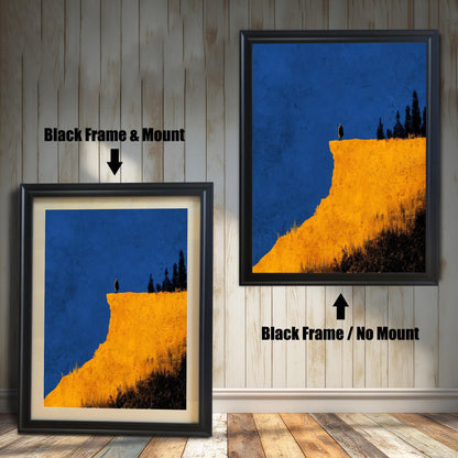 Comparison image showing the Black frame options for the cliff print: on the left, a framed print with a cream-colored mount/mat; on the right, the print in a black frame with no mount. Both on a rustic wooden wall background.