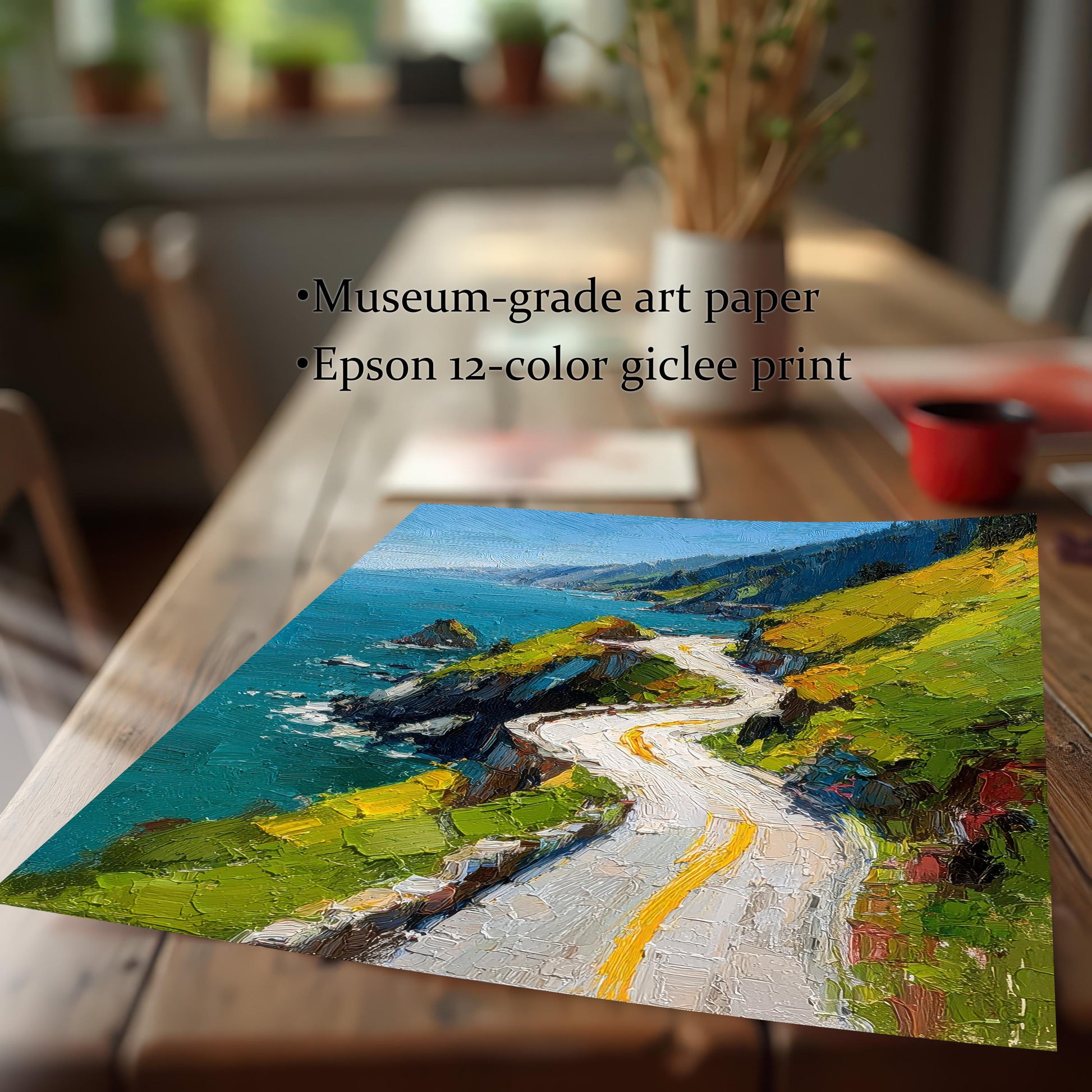 A close-up of a high-quality print of the coastal road art, featuring thick, visible brushstrokes. Text highlights the quality: Museum-grade art paper and Epson 12-color giclee print. The print rests on a wooden table.