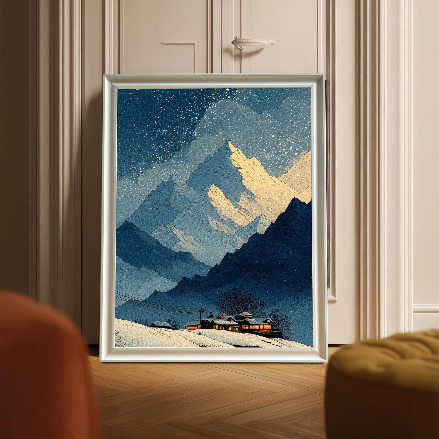 A framed art print of the snowy mountain landscape, displayed leaning against a door with decorative molding. The frame is White wood.