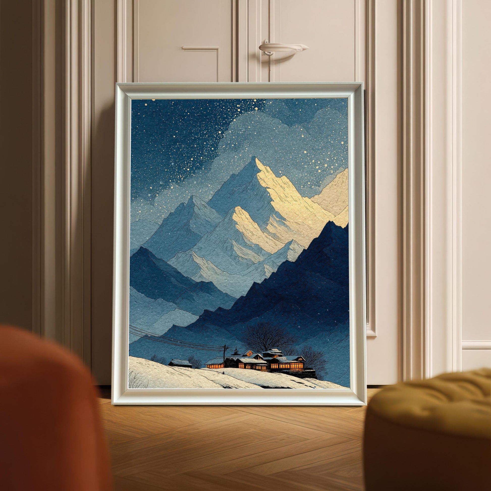 A framed art print of the snowy mountain landscape, displayed leaning against a door with decorative molding. The frame is White wood.
