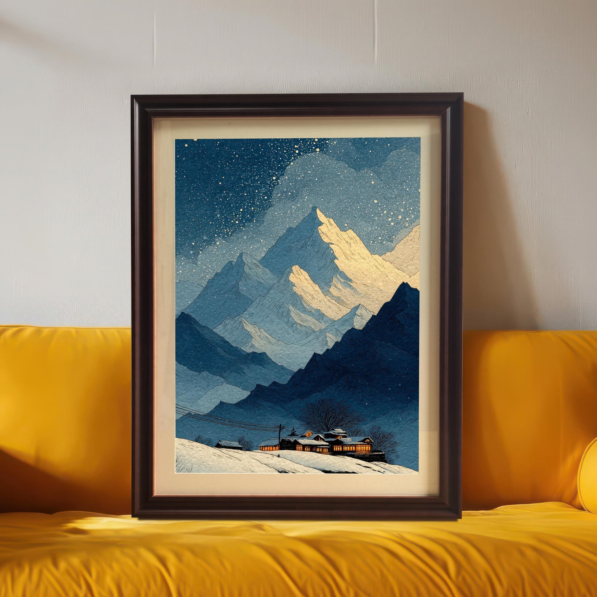 A framed art print of the snowy mountain landscape, leaning against a gray wall and resting on a bright yellow sofa. The frame is a dark brown (Coffee) wood with a light border/mount.