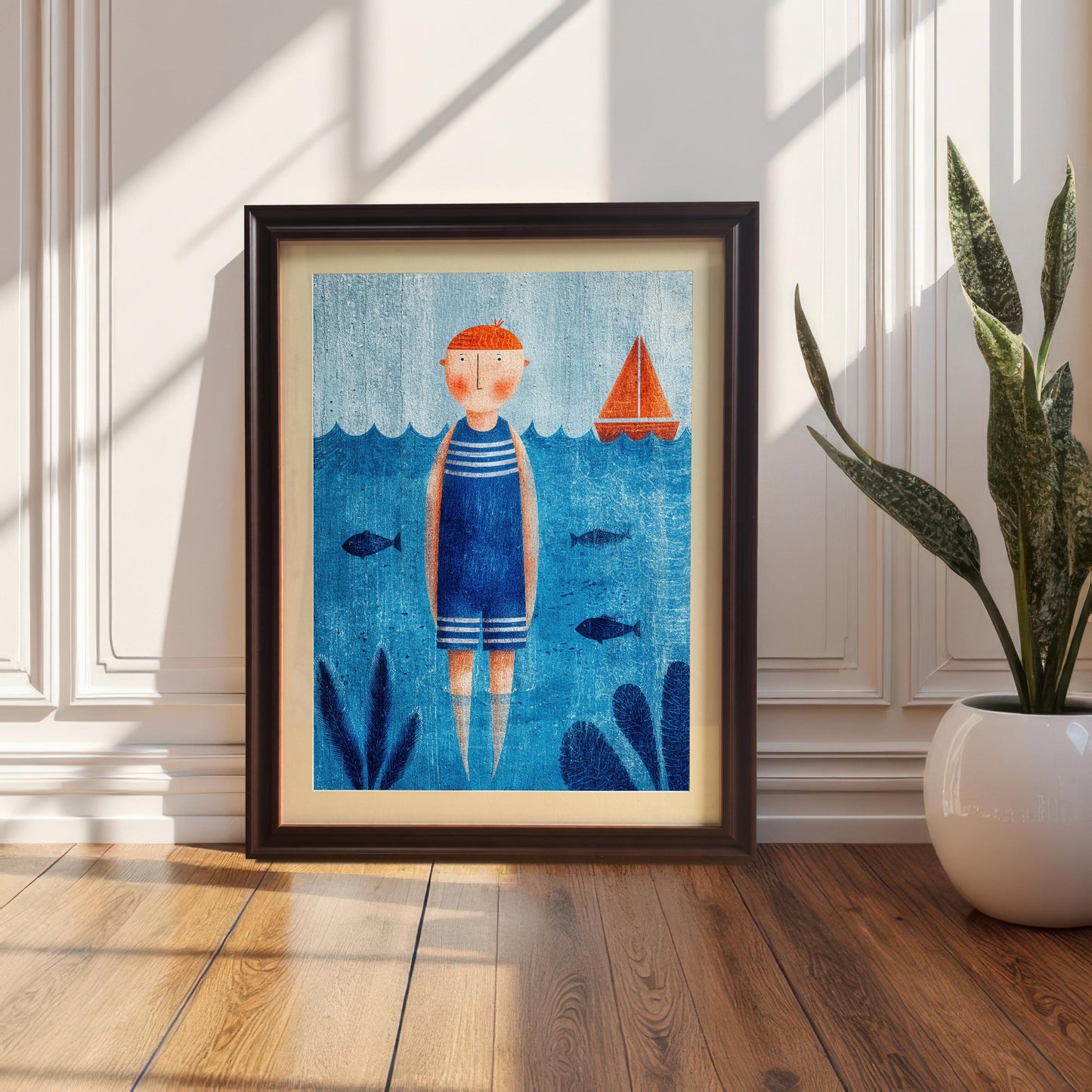 A framed nautical art print featuring a person in a blue and white striped swimsuit standing in the water, leaning against a white wainscoted wall on a wooden floor. The frame is black with a white mount. A tall potted snake plant is visible to the right.
