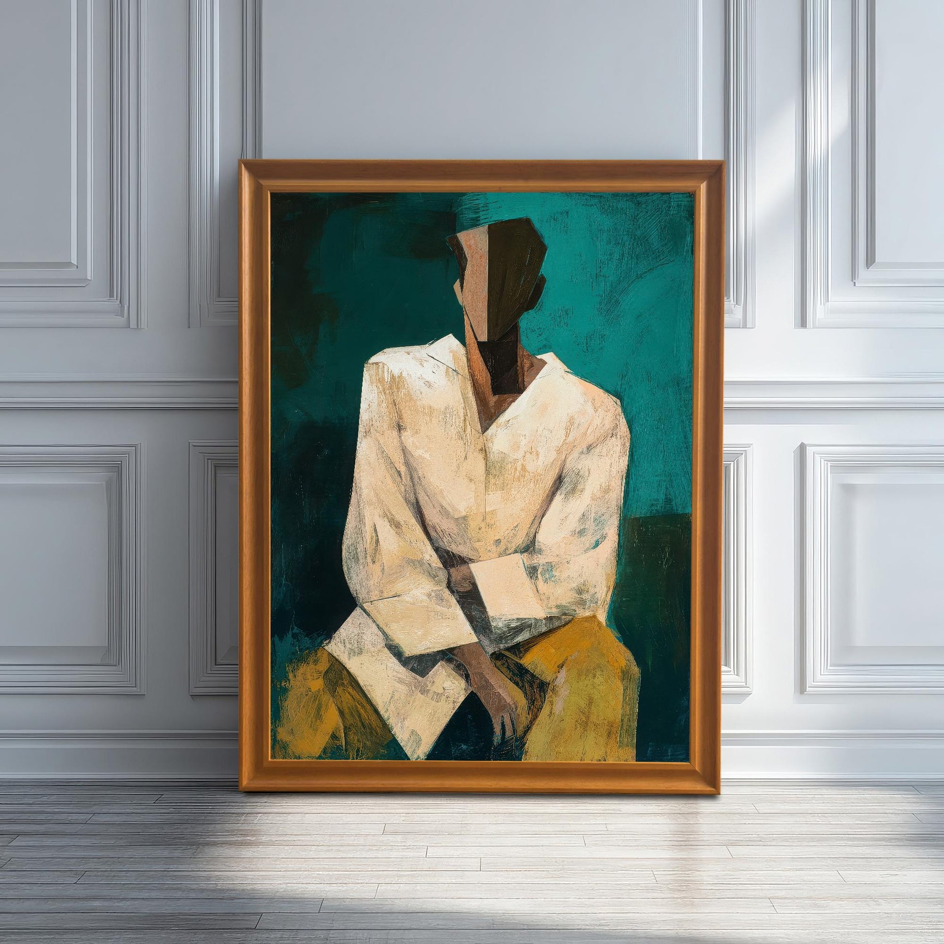 A large, framed abstract portrait print in a light brown/orange frame, leaning against a white wainscoted wall on a light wooden floor.