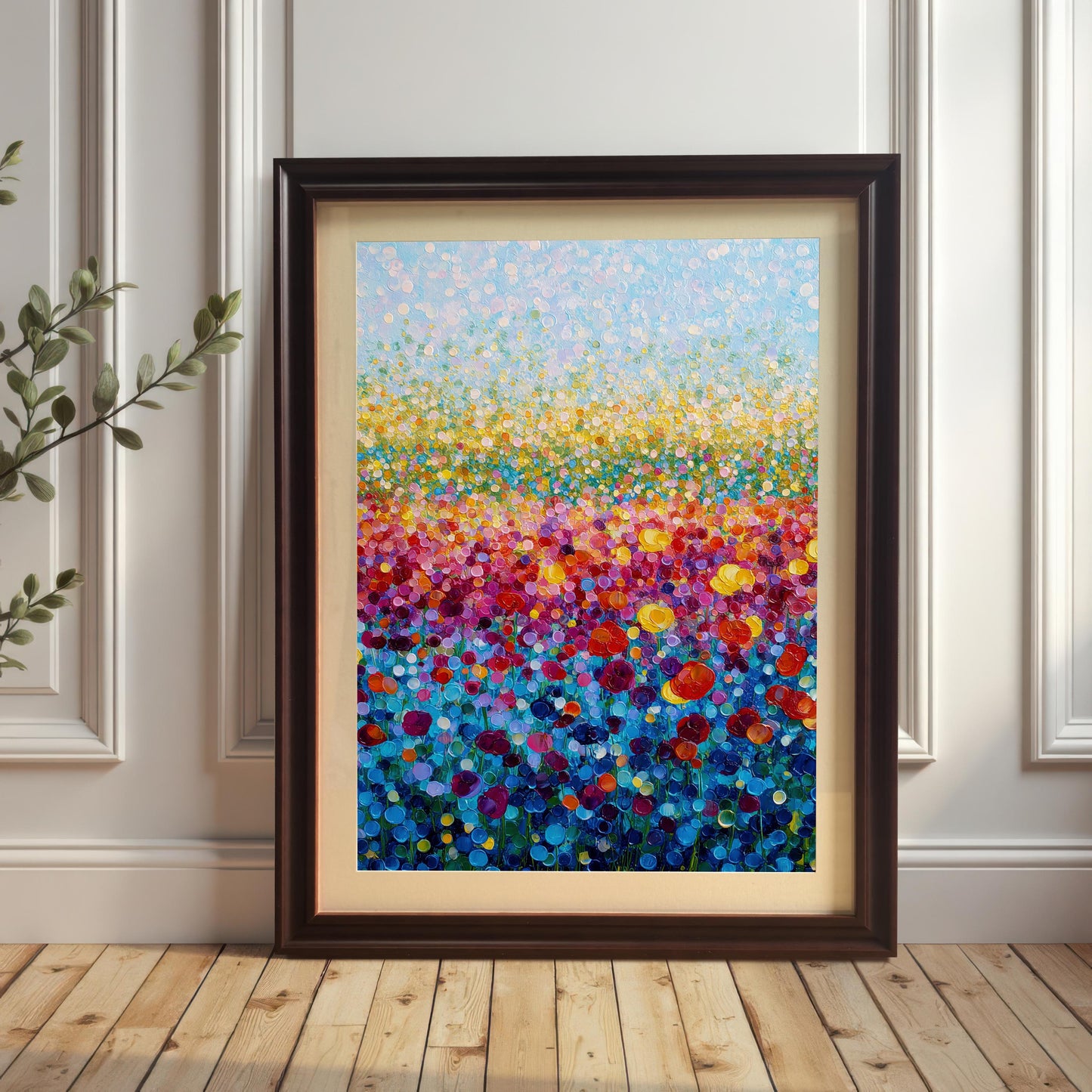 Bright abstract flower field print in a dark coffee wood frame with a light mount, leaning on a wood floor against a white paneled wall.