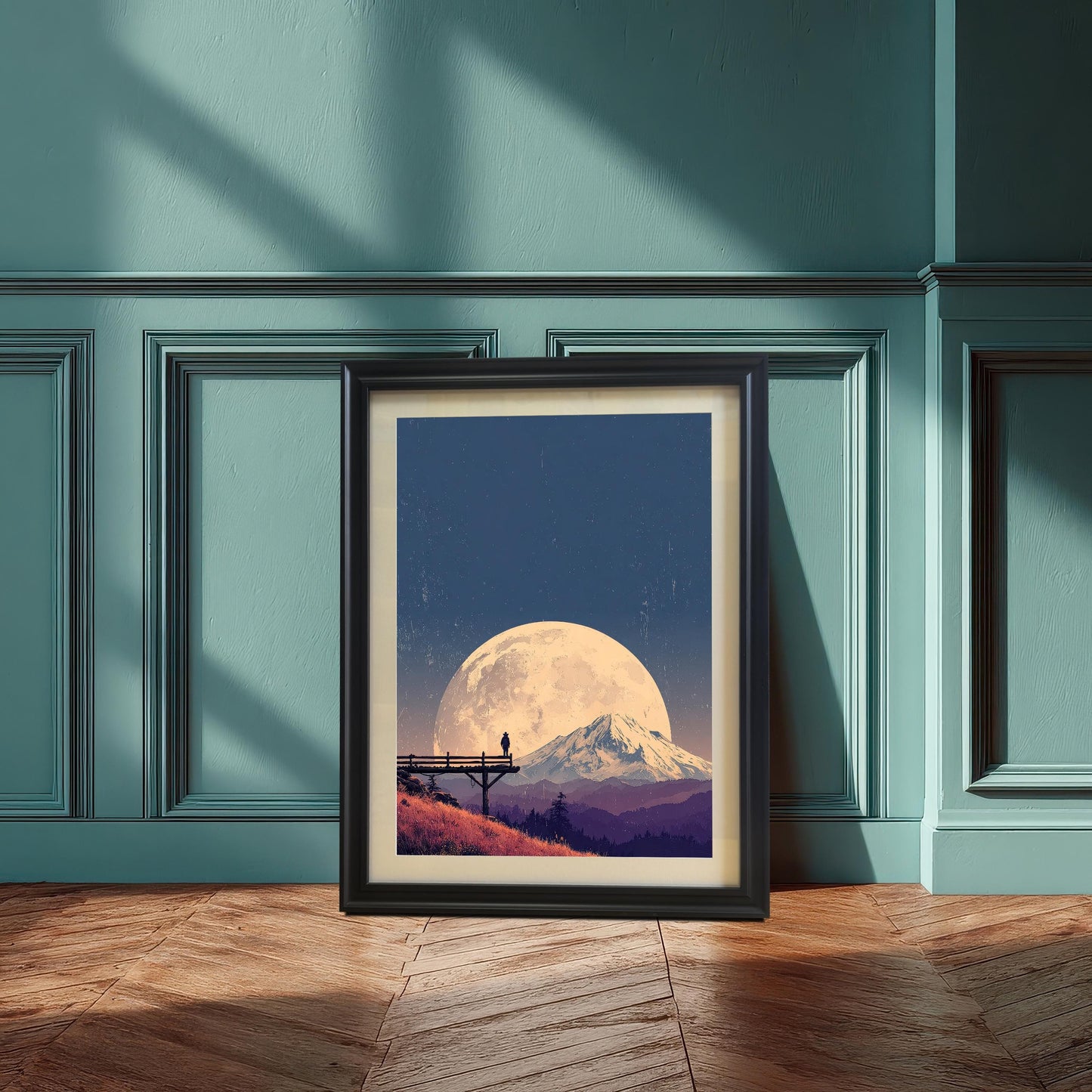 Landscape art print in a black frame with a mount, featuring a large moon over a mountain, leaning on the floor against a paneled teal/blue wall.