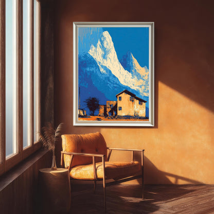 Large landscape art print in a white/silver frame, featuring stylized blue mountains and an orange house, hanging in a room with an orange wall above a leather armchair.
