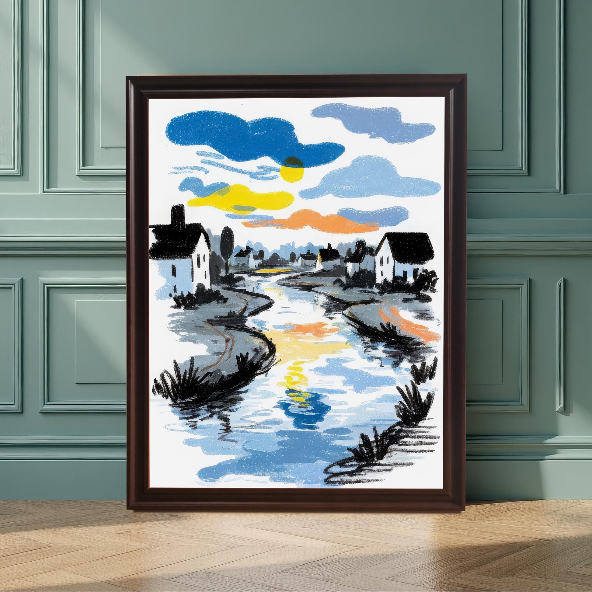 The framed sketch-style art print, featuring a river reflecting a colorful sunset/sunrise sky, lined with white houses. It is leaning on a wooden floor against a paneled wall painted seafoam green/dark teal. The frame is a dark Coffee color with a mat/mount.