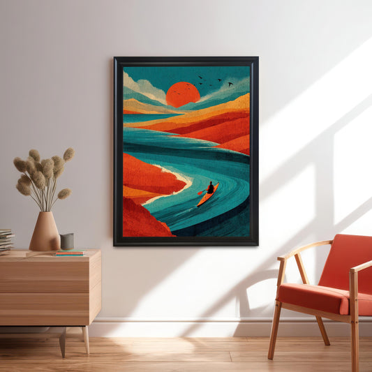 A large black-framed vibrant landscape art print of a person kayaking at sunset, hung on a white wall in a modern living room with a mid-century chair.