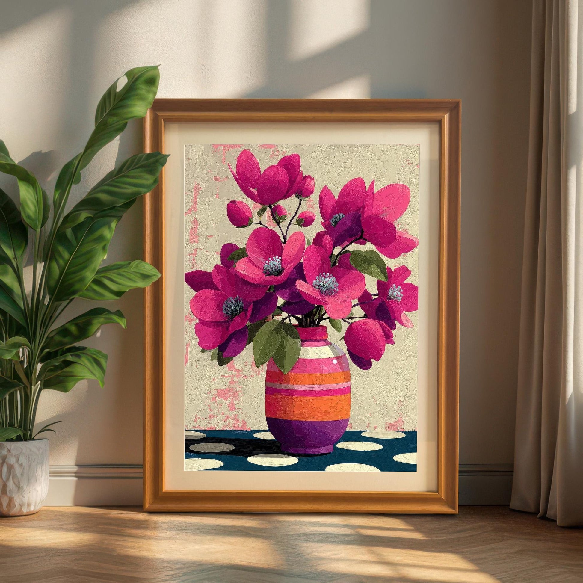 Large orange-framed floral print with a white mount leaning against a wall next to a green houseplant.