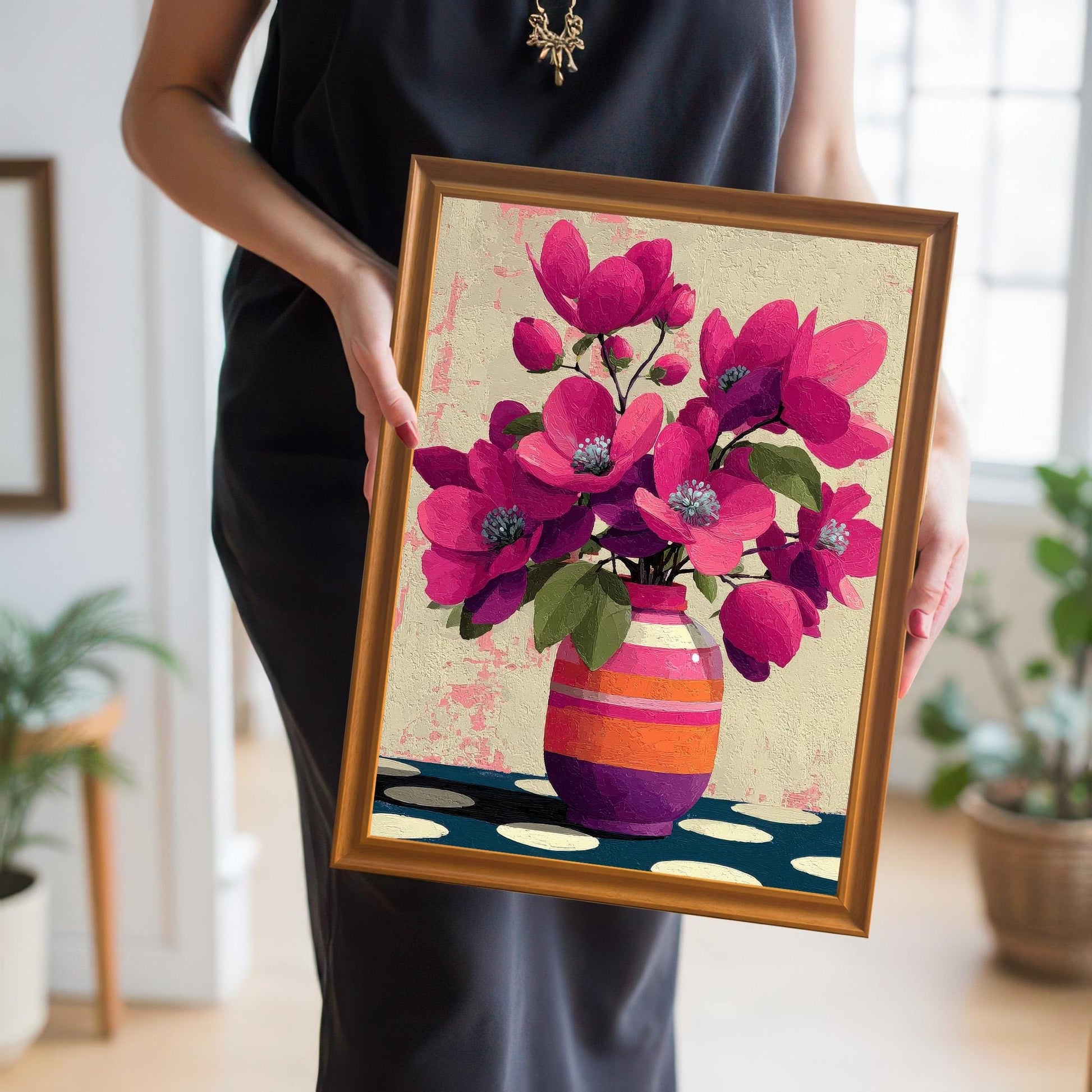 A person holding a medium-sized orange-framed art print of pink flowers to show scale and frame quality.