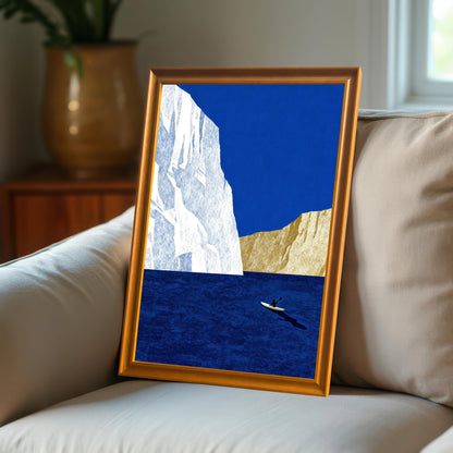 An orange wood-framed minimalist sea print leaning against a beige cushion on a couch in a cozy, sunlit interior.