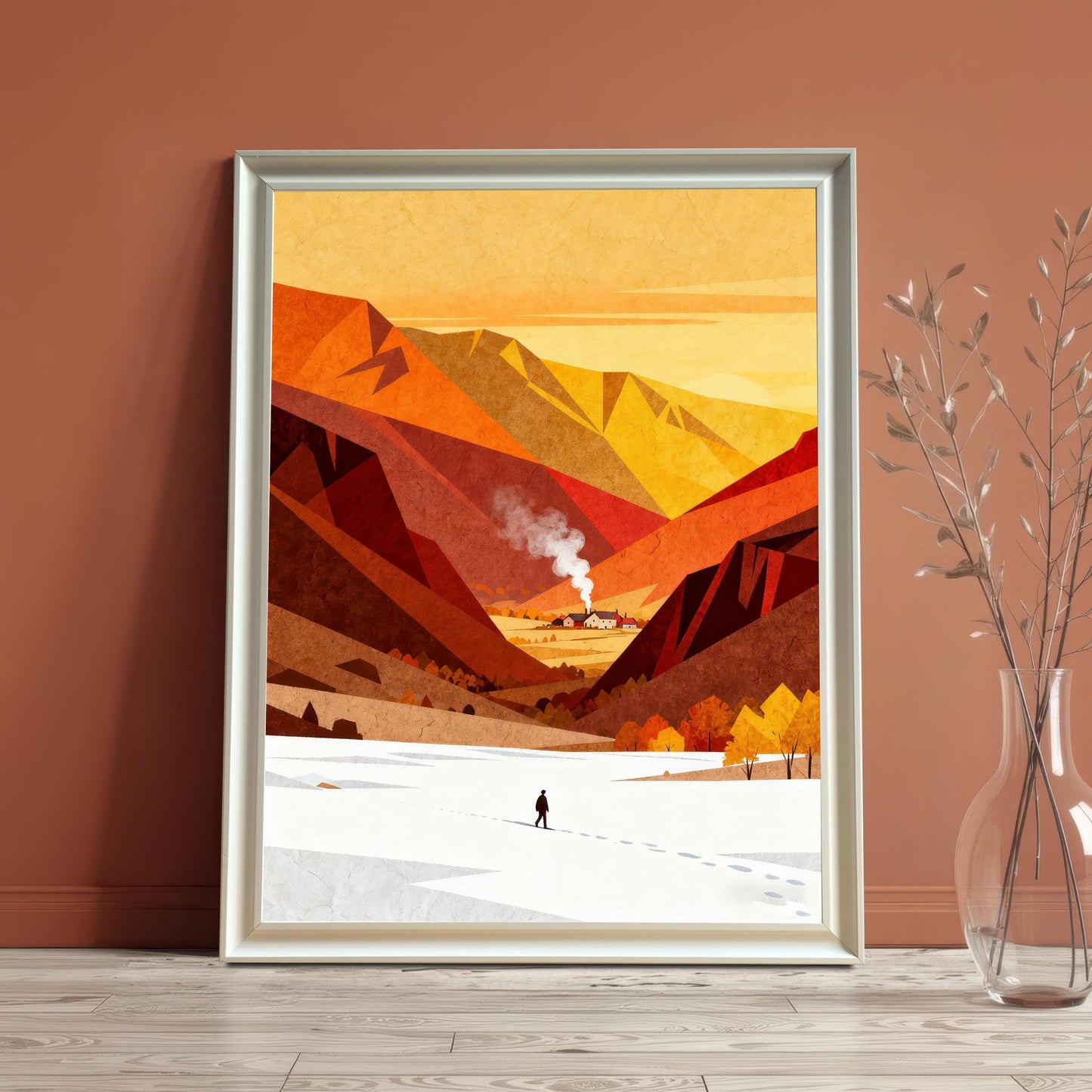 Vibrant orange and red mountain art print in a white wooden frame, standing on a light wood floor against a terracotta-colored wall next to a glass vase with dried branches.