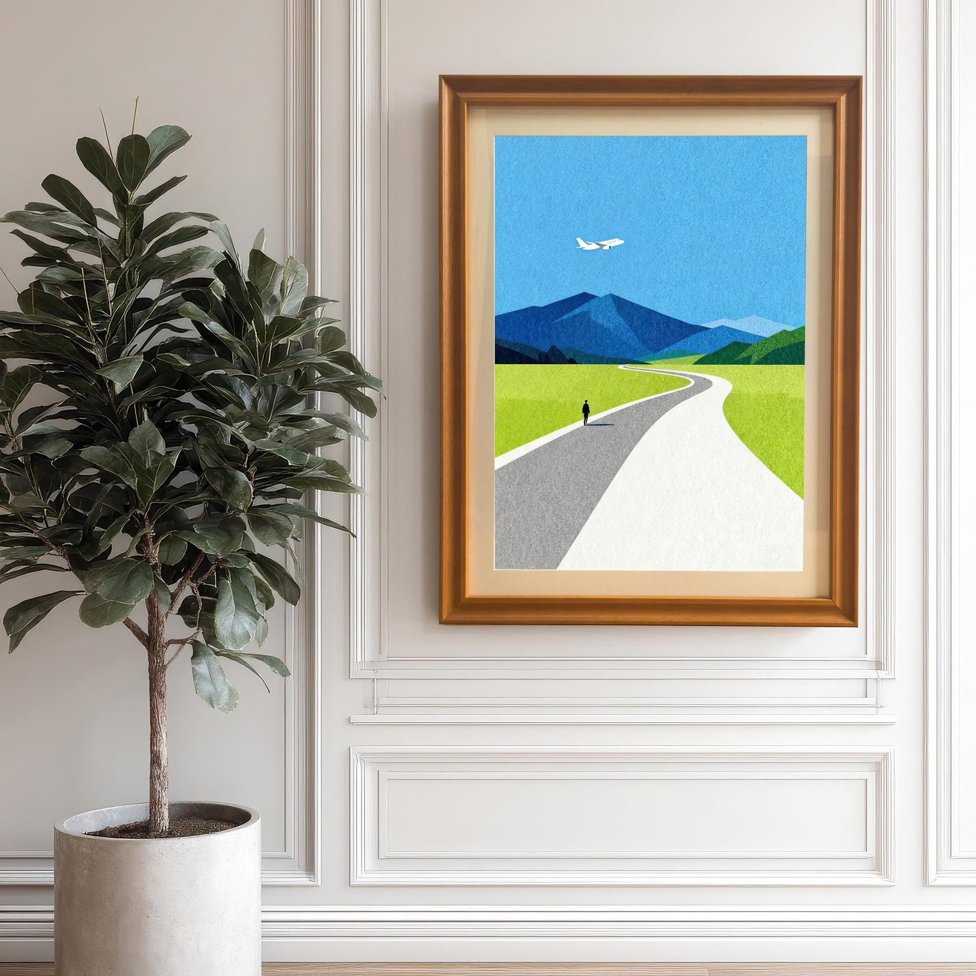 A vertical landscape art print in an orange wood frame with a mount, hanging on a classic white paneled wall next to a large indoor fiddle leaf fig plant.