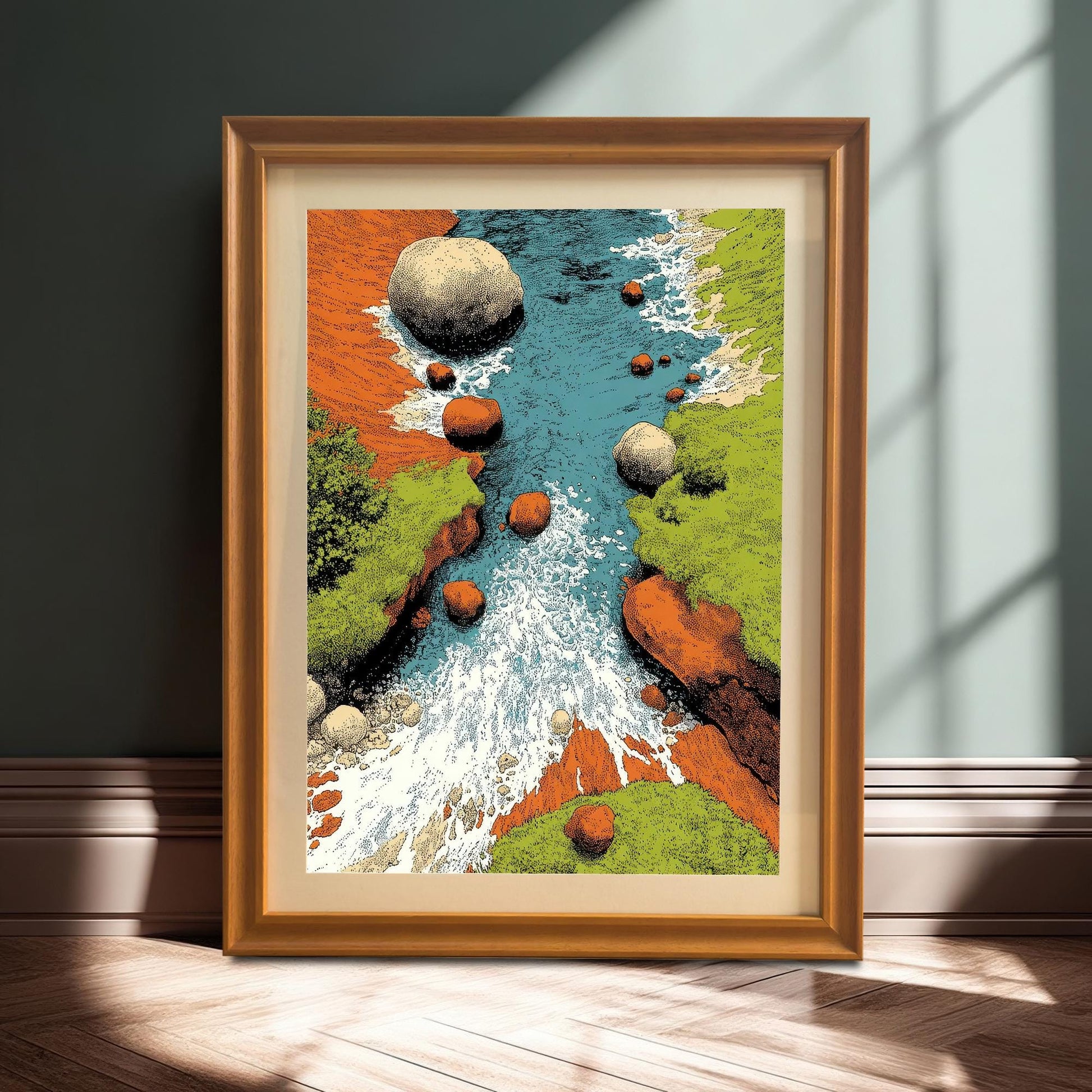 A framed art print with an orange/light wood frame and a mount/matting, leaning against a dark teal wall on a wooden floor with dramatic shadows. The art features a stylized river/stream with bright colors and rocky banks.