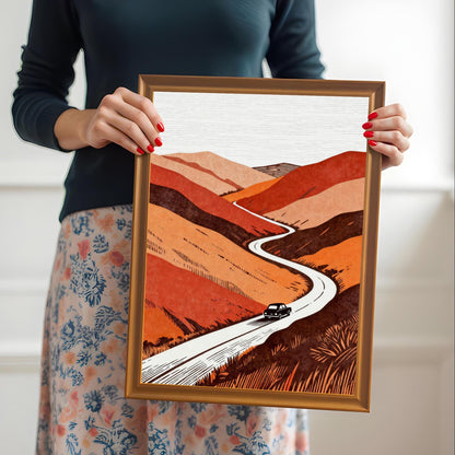 A person holding the orange-framed art print to provide a real-world sense of scale and showing the vibrant colors of the winding road illustration.
