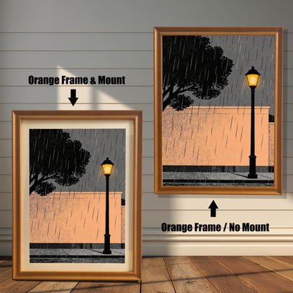 Comparison of the orange wood frame option showing two versions: one with a white mat board (mount) and one without, featuring an illustration of a street lamp in the rain against a peach wall.