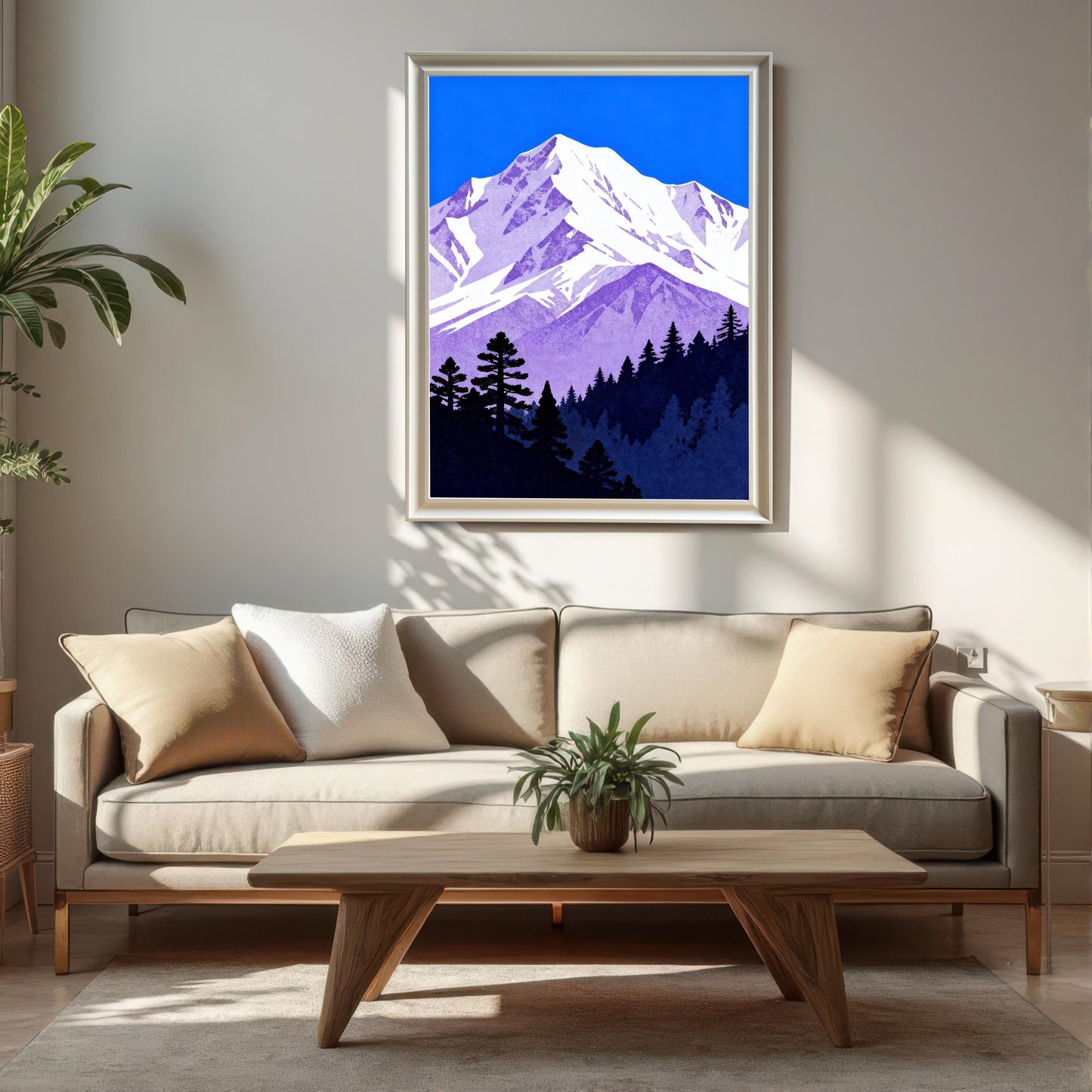 The purple and blue mountain art print in a 'White' wood frame, hanging on a light-colored wall above a beige sofa and a wooden coffee table in a modern living room setting.