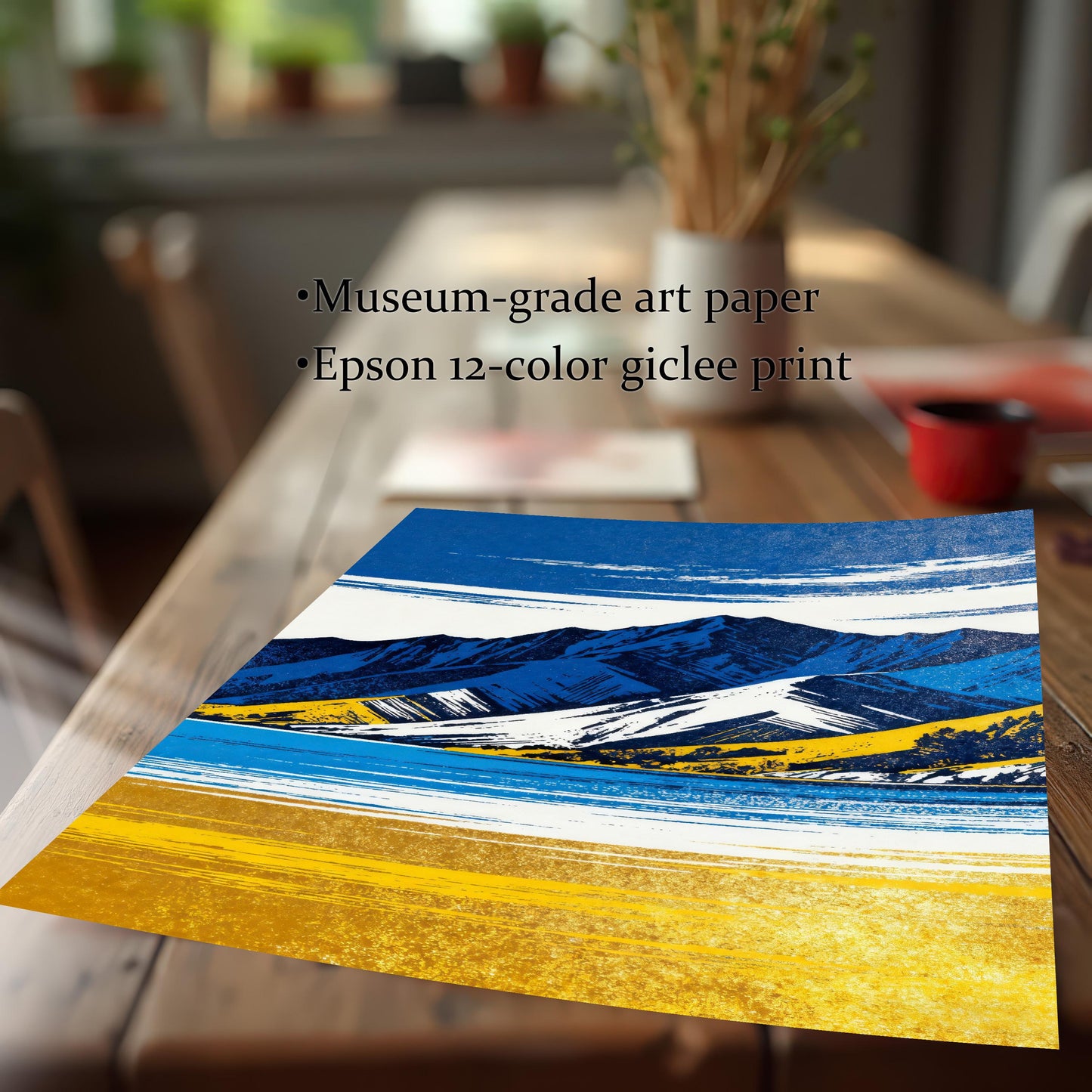 A close-up, angled view of an unframed print of the blue and yellow mountain landscape, lying on a wooden table. Text highlights the quality: "Museum-grade art paper" and "Epson 12-color giclee print".
