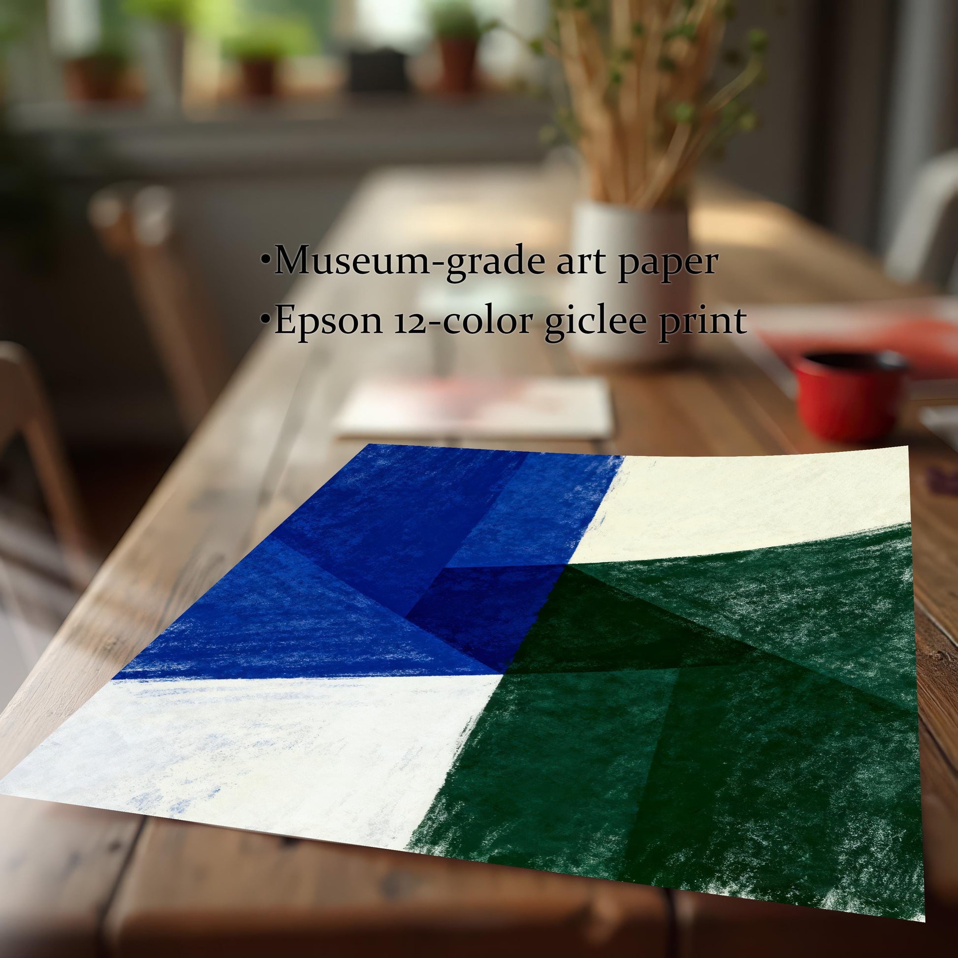 Close-up of an unframed art print with a geometric abstract design in blue, green, and cream colors, resting on a wooden table. Text overlays highlight features: Museum-grade art paper and Epson 12-color giclee print.