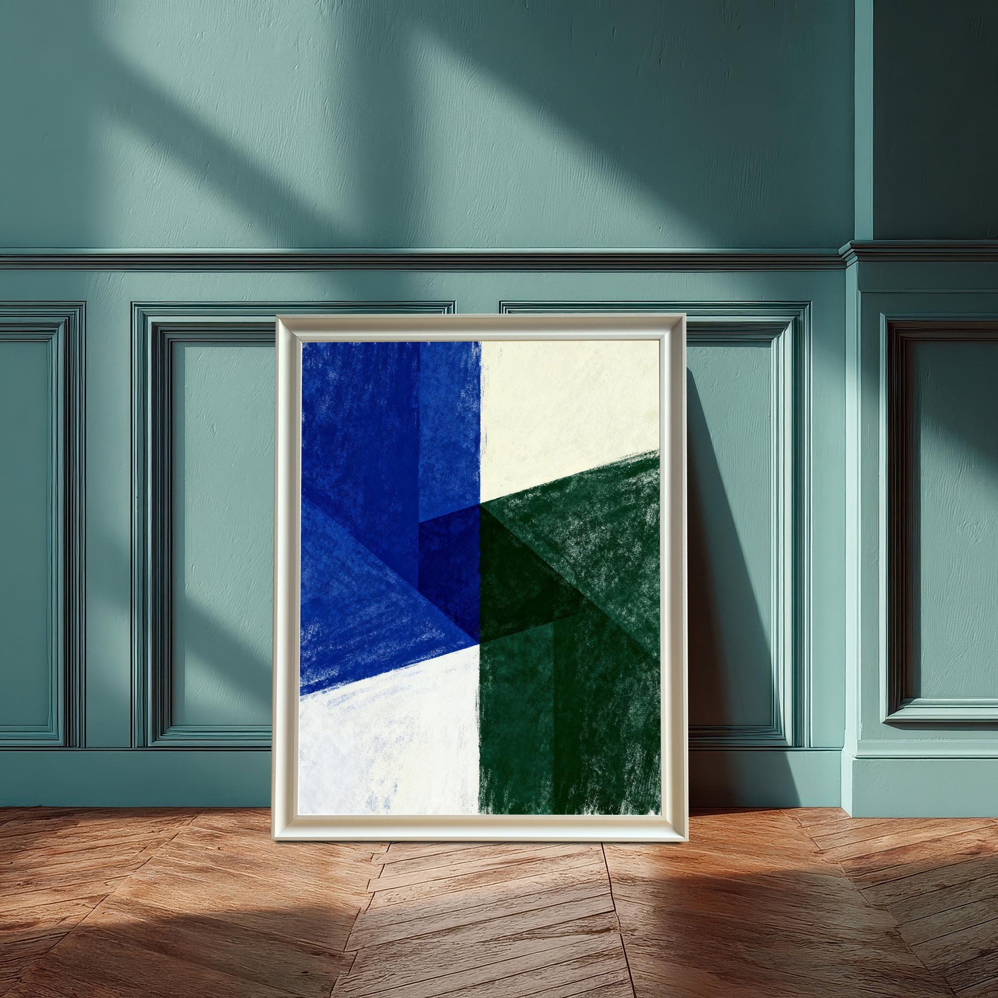 Abstract art print with geometric shapes in dark blue, deep green, and off-white. The print is showcased in a White Frame and is leaning against a textured teal wall with wainscoting, on a wood floor with sunlight streaming in.