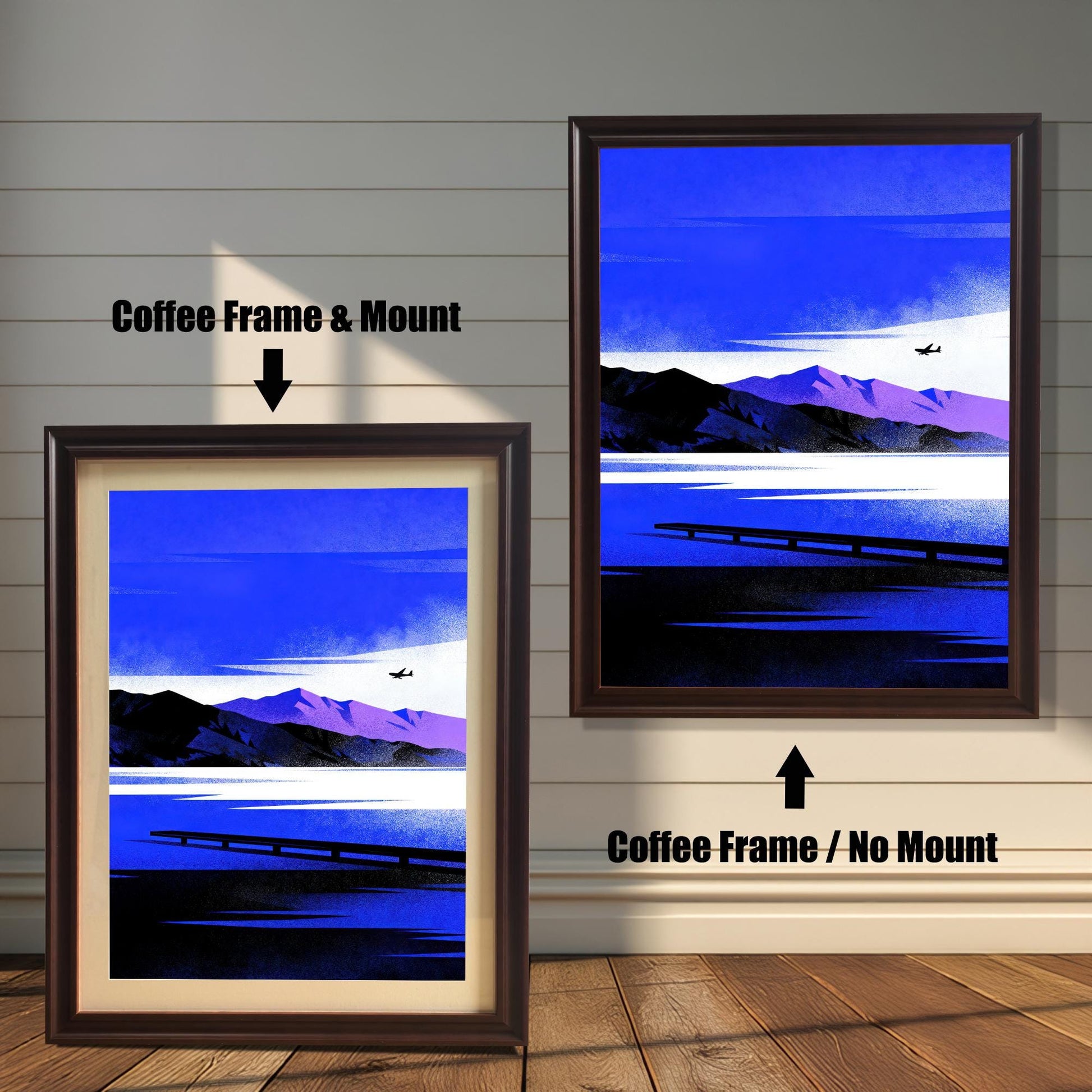 Comparison image of two framed art prints against a light wooden wall. The left print shows a Coffee Frame & Mount (with a beige border/mat). The right print shows a larger Coffee Frame / No Mount. Both display the same stylized artwork of a blue and purple mountain lake scene with an airplane