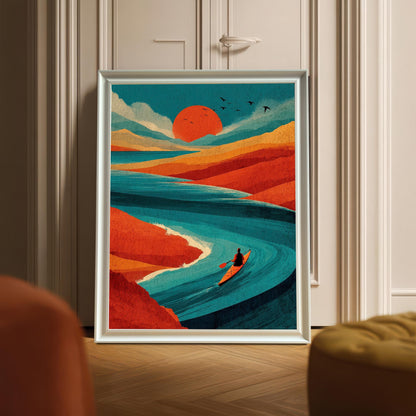 A white-framed art print of a person kayaking on a teal river under a large red sun, leaning against a white paneled door on a herringbone wood floor.