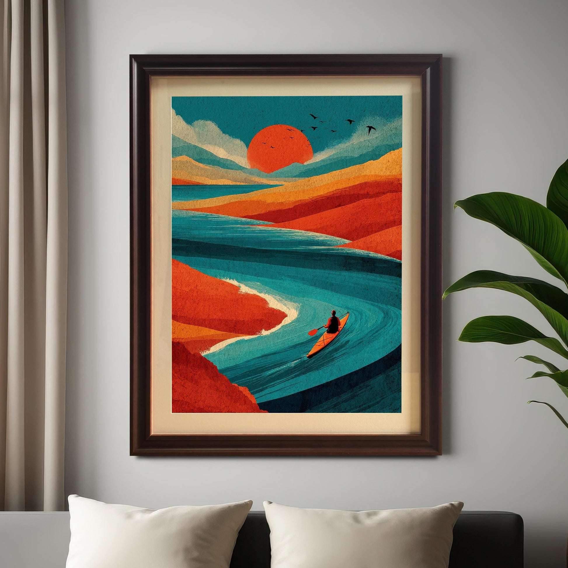 A coffee-colored wood-framed art print of a vibrant sunset river scene hanging above a bed with white pillows, next to a large green indoor plant.