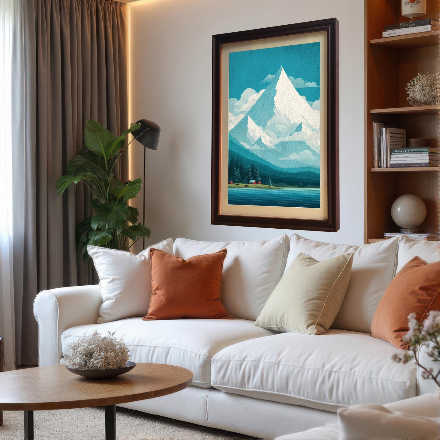 A large, dark wood-framed mountain print with a wide mat mount hanging as a focal point in a modern living room above a white sofa with orange accent pillows.
