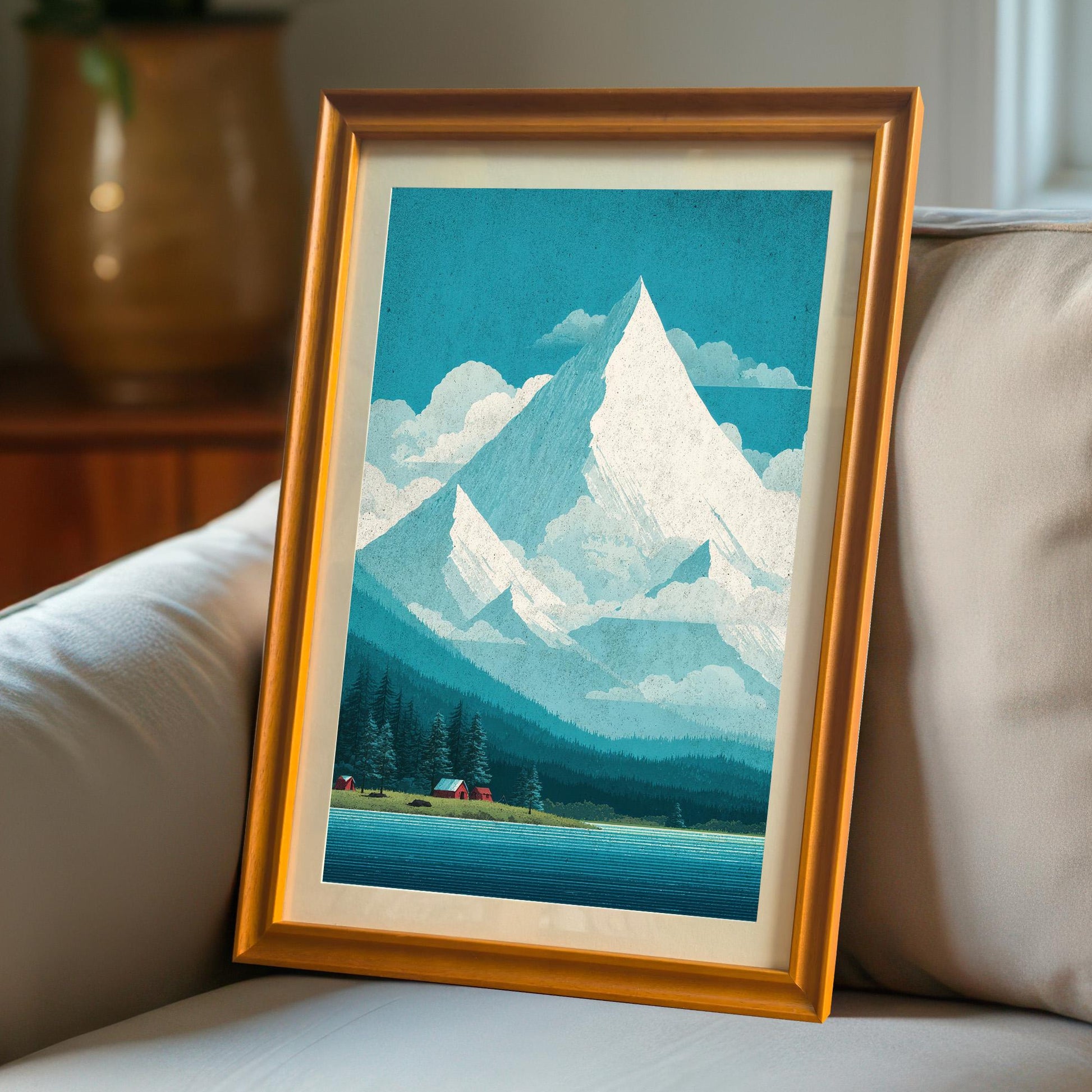 An orange-wood framed art print with a mat mount leaning against a grey couch, showing the artwork in a cozy, natural lighting home setting.