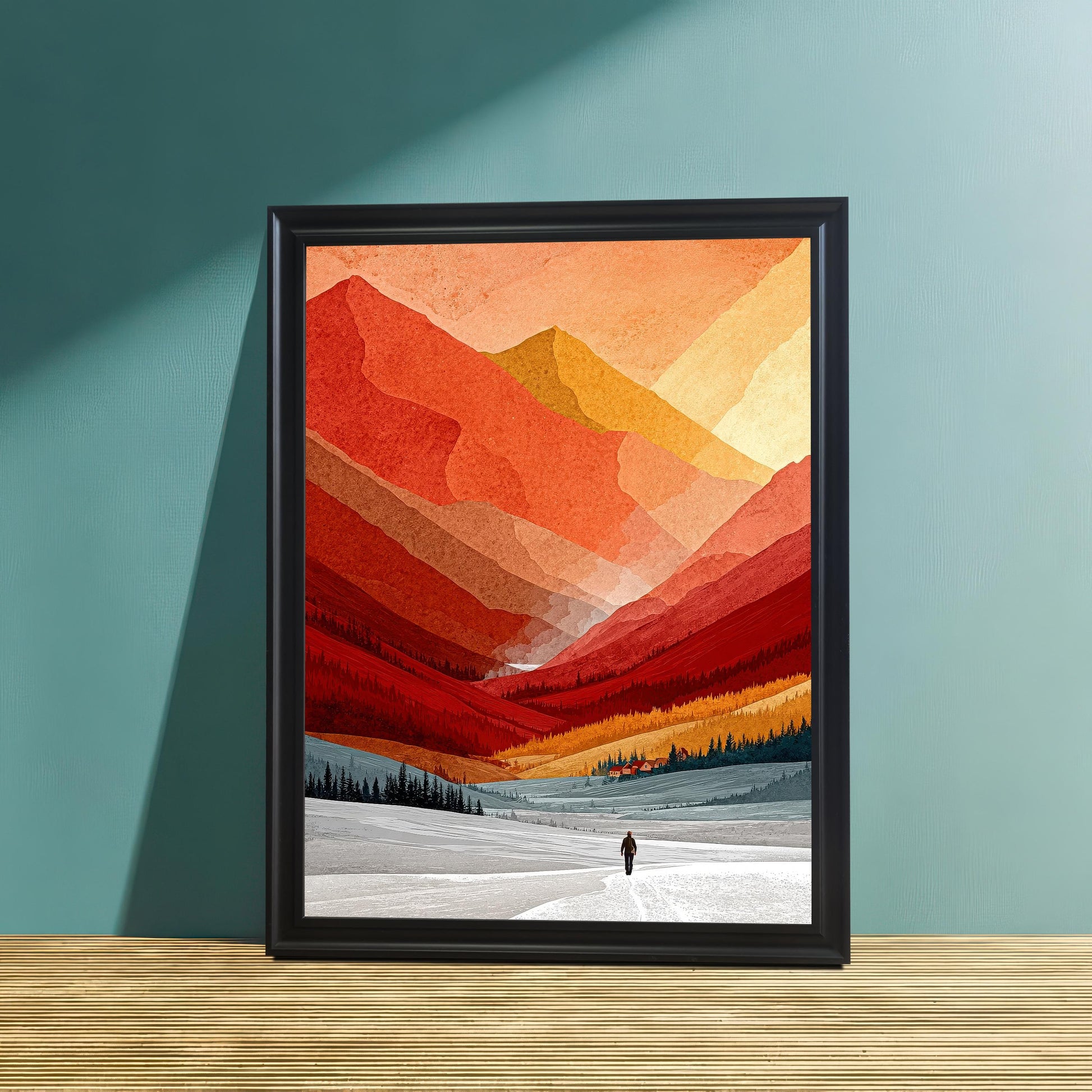 Vibrant orange and red mountain landscape print in a minimalist black wood frame, leaning against a teal-colored wall on a textured wooden surface.
