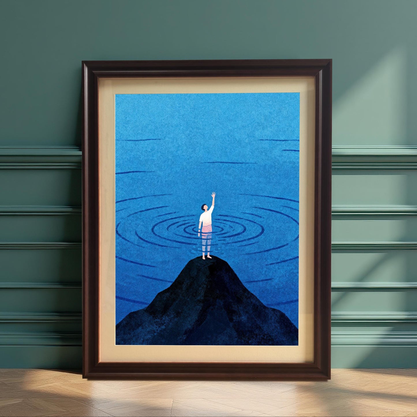 A vertical wood-framed art print in a dark coffee finish leaning against a teal-paneled wall on a light wood floor. The artwork features a minimalist illustration of a person standing on a dark peak amidst blue rippling water.